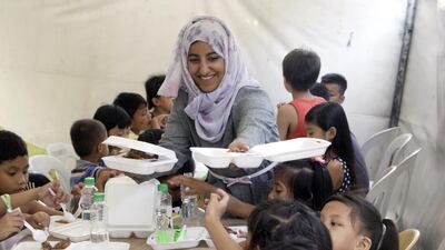 Tasneem Alnaqbi hands out food to Filipino children as her journey, and that of five other young Emiratis, draws to a close. Courtesy Beyond Borders