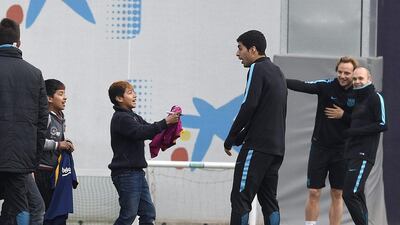 Barcelona’s Uruguayan forward Luis Suarez (C) signs autographs for children who gate-crashed the training session at the Sports Center FC Barcelona Joan Gamper in Sant Joan Despi, near Barcelona on March 14, 2016, on the eve of the Uefa Champions League last sixteen second leg football match between FC Barcelona and Arsenal. AFP / LLUIS GENE