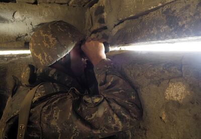 An ethnic Armenian soldier looks towards Azerbaijan's positions from a dugout at a fighting position on the front line in Nagorno-Karabakh, on October 21, 2020. AP