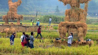 Tourists take pictures of straw figurines of traditional deities Shennong, right, and Zhang Wulang, left back, during China’s National Day Holiday, in Xinhua county, Hunan province. China Daily / Reuters