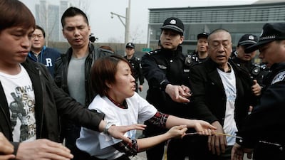 Scuffles broke out when uniformed security personnel attempted to block some of the relatives from reaching reporters, who were being kept in a designated area. One woman was taken away on a stretcher. Lintao Zhang / Getty Images