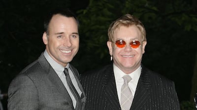 David Furnish and Elton John, in a pin-striped suit, arrive at Sir David Frost's summer party on July 5, 2007 in London. Getty Images