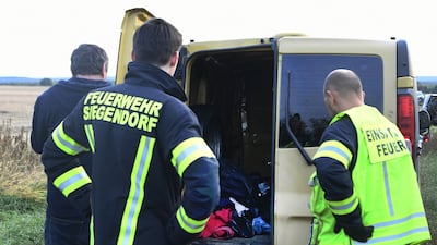 Austrian firemen inspect the van where two migrants were discovered dead. APA