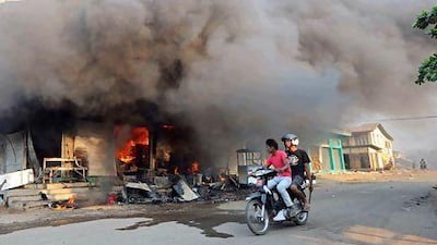 Residents ride a motorcycle past a burning building in riot-hit Meiktila, central Myanmar. At least 36 people have been killed in anti-Muslim rioting since Wednesday. Soe Than Win / AFP Photo