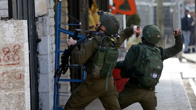 Israeli soldiers throw sound bombs as they clash with Palestinians during a search for suspects of a shooting attack yesterday in the West Bank City of Ramallah, Monday, December 10, 2018. AP