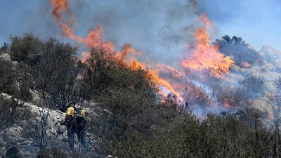Flames from a brush fire flare around a firefighter in San Bernardino, California. James Quigg / The Daily Press via AP