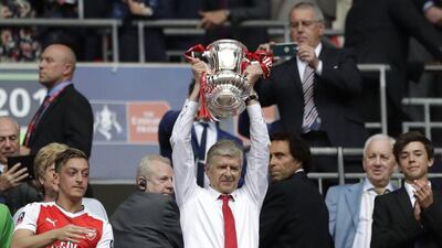 Arsene Wenger holding aloft the FA Cup trophy at the end of last season. Wenger led his side to silverware but they slipped out of the Premier League top four. Agencies