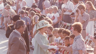 The queen greets a teacher at the school as pupils look on.