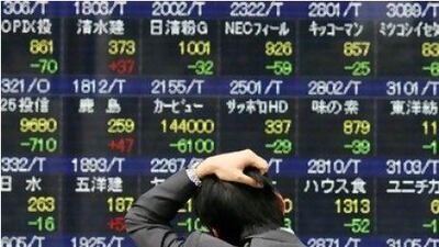 A Japanese worker looks on in disbelief as stock prices plummet in Tokyo yesterday.
