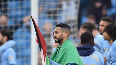 Riyad Mahrez wears the flag of Algeria while carrying the flag of Palestine on Sunday. Getty