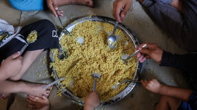 Displaced Palestinians share food provided by a charity kitchen in Khan Younis, southern Gaza. AFP