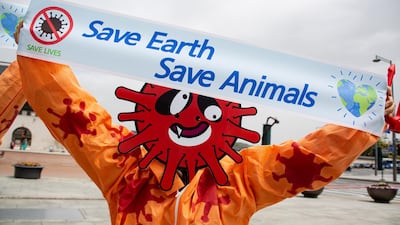 A member of the Environmental Health Citizens' Association of Korea, wearing a mask representing the Sars-CoV-2 coronavirus, holds a banner during the 50th anniversary of Earth Day, at Gwanghwamun Square in Seoul, South Korea. EPA