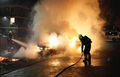 Firefighters extinguish a vehicle set on fire by rioters, in Haarlem, Netherlands. (Mizzle Media via AP)