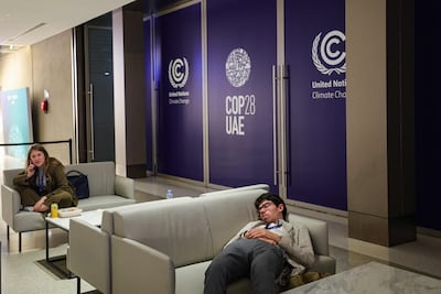 A Cop28 participant rests on a couch. The past two weeks of climate talks have been demanding and protracted. AFP