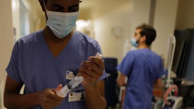 Nurse Hyad Boina, left, prepares a syringe to use in the treatment of a patient in room No. 9 in his battle against COVID-19 at Bichat Hospital, AP-HP, in Paris. AP Photo