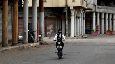 A man cycles past shops in Baghdad, Iraq, that were shut to curb the spread of the coronavirus. AP