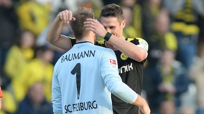 Borussia Dortmund captain Sebastian Kehl embraces Freiburg keeper Oliver Baumann after beating him for a goal during Dortmund's 1-0 win on Sunday. Patrick Seeger / EPA / March 9, 2014