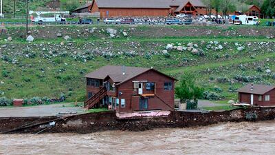 The flooding Yellowstone River undercuts the river bank, threatening a house and a garage in Gardiner, Montana. Sam Glotzbach / AP