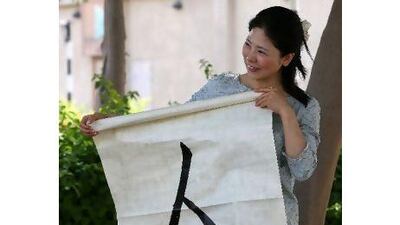 Kikumi Nakagawa, who lives in Dubai, is collecting funds for relief efforts in her homeland. She is holding a calligraphic painting whose symbol represents 'human being'.
