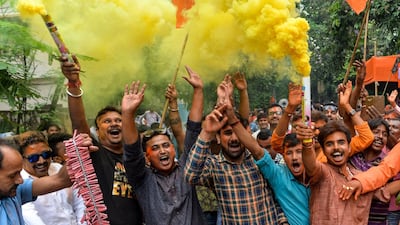 Indian supporters of Bharatiya Janata Party (BJP) hold colour smoke crackers as they celebrate the vote results. AFP