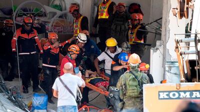 Rescue workers carry a survivor out of the collapsed Chuzon supermarket in Porac, Pampanga. AFP