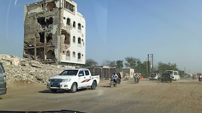 Cars and motorcycles move past a building damaged by clashes on the outskirts of the Red Sea port city of Hodeidah, Yemen. Photo: Reuters
