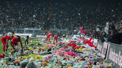 Players from Besiktas and Antalyaspor move toys to side of pitch after fans threw them down from stands. AP