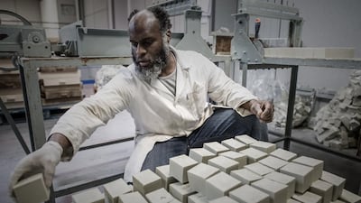 An employee of the Aleppo soap company Alepia sorts out bars of soap in Santeny, 30kms from Paris, on December 19, 2016. / AFP PHOTO / PHILIPPE LOPEZ