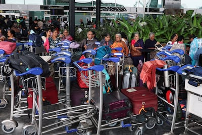Travellers sit with their luggage at Kempegowda International Airport in Bengaluru, India, on December 6, 2025. Reuters