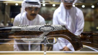 Visitors at the Abu Dhabi 2025 International Hunting and Equestrian Exhibition examine a .308 calibre hunting rifle made by Merkel. The hand engraving, which shows the Dubai skyline surrounded by date palms and sand dunes, took 300 hours. Victor Besa / The National Victor Besa / The National