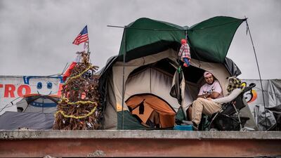 A US flag stands on top of a Christmas tree near a tent of migrants at the Barretal shelter for Central Americans who arrived in caravans over the past two months and hope to enter the US, in Tijuana, Mexico. AP Photo