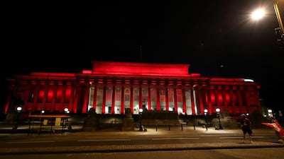 Liverpool fans celebrate outside St George's Hall which is lit up red. PA