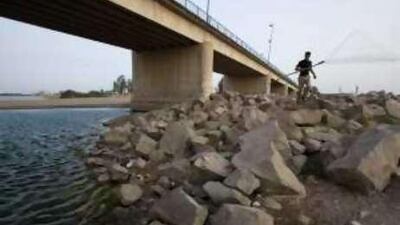 A fisherman walks down to the Euphrates River during the spawning season when fishing is illegal, near a new bridge in Raqqa City, Syria. Illegal hunting and fishing have hit the environment hard in the area.