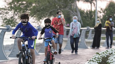 Two boys on their bikes speed along the Corniche-Marina Mall pathway as the sun sets in Abu Dhabi. Victor Besa / The National