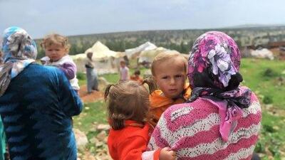 Syrian women carry their children near their makeshift refugee camp in the mountains in the area of Kherbet Al Khaldiye, on the Syria-Turkey border.