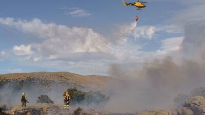 A helicopter drops water as fires blaze between Navalcruz and Riofrio near Avila, central Spain, on August 15. AFP