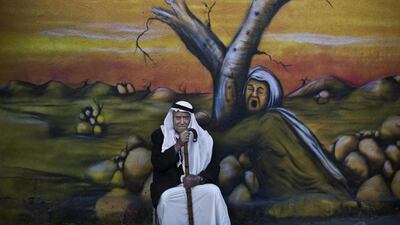 Palestinian refugee Mohammed Emtair, 85, poses for a picture in front of a mural depicting the Israeli-Palestinian conflict, in the Kalandia refugee camp between Jerusalem and the West Bank city of Ramallah.