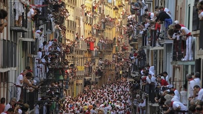 People watch participants from balconies as they run in front of Alcurrucen's bulls during the first bull run of the San Fermin Festival, on July 7 in Pamplona, northern Spain. Pedro Armestre / AFP