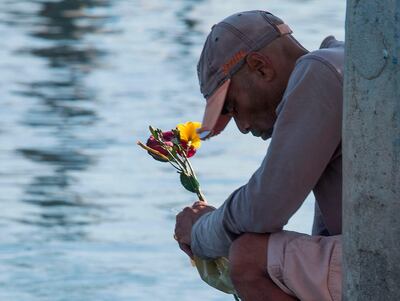 A man prays and drops flowers into the water at Santa Barbara Harbour. AFP