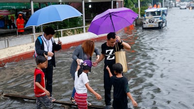 Commuters cross on a wooden plank for a fee to avoid a flooded street after heavy rains brought about by tropical storm 'Nesat' flooded some parts of metropolitan Manila. Bullit Marquez / AP Photo