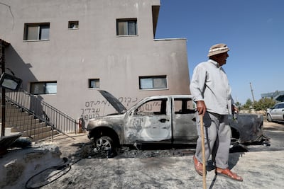 A Palestinian inspects the damage after Israeli settlers set fire to a car in Deir Abu Mashal, north-west of Ramallah, in the occupied West Bank. EPA