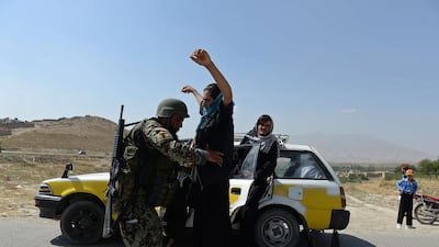 An Afghan soldier searches passengers at a checkpoint near the Marshal Fahim National Defense University, a training complex on the outskirts of Kabul on August 6. A US general was shot dead in Afghanistan in an "insider attack" that left more than a dozen wounded including a senior German officer. Marai Shah / AFP