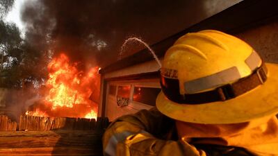 A Los Angeles County firefighter puts water a burning house in a wildfire in the Lake View Terrace area of Los Angeles. Chris Carlson / AP Photo