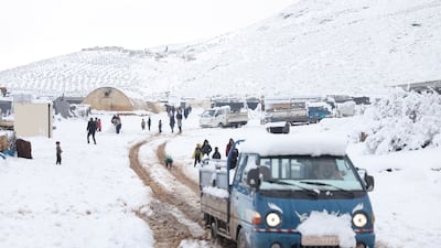 Internally displaced Syrians stand in the snow
