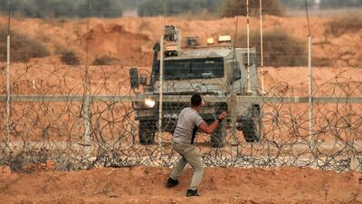 A Palestinian protester hurls stones at a vehicle during clashes with Israeli forces following a demonstration along the border with Israel east of Khan Yunis in the southern Gaza strip. AFP