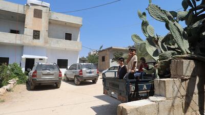 Children sit in the bed of a lorry in front of a house, the site of a reported joint operation by the US-led coalition, in the town of Atme in north-west Syria on August 20, 2025. AFP
