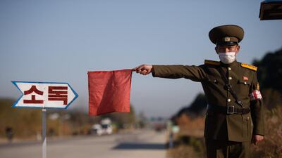 A public security officer uses a red flag to stop a taxi for disinfection on a road at the entrance to Wonsan, Kangwon Province. AFP