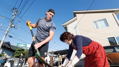 Canadian rugby player Josh Larsen, left, helps a resident to clean a road in Kamaishi, Iwate prefecture, Japan, following the cancellation of their Rugby World Cup Pool B match against Namibia due to Typhoon Hagibis. The powerful typhoon unleashed torrents of rain and strong winds Saturday that left thousands of homes on Japan's main island flooded, damaged or without power. AP