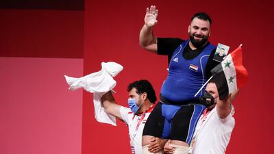 Man Asaad of Syria is lifted by his coaches after winning a bronze medal in the men's +109kg weightlifting.