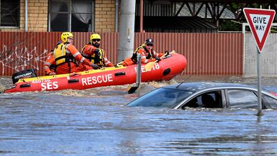 Emergency workers pass a submerged car on a flooded street in the Melbourne suburb of Maribyrnong. AFP
